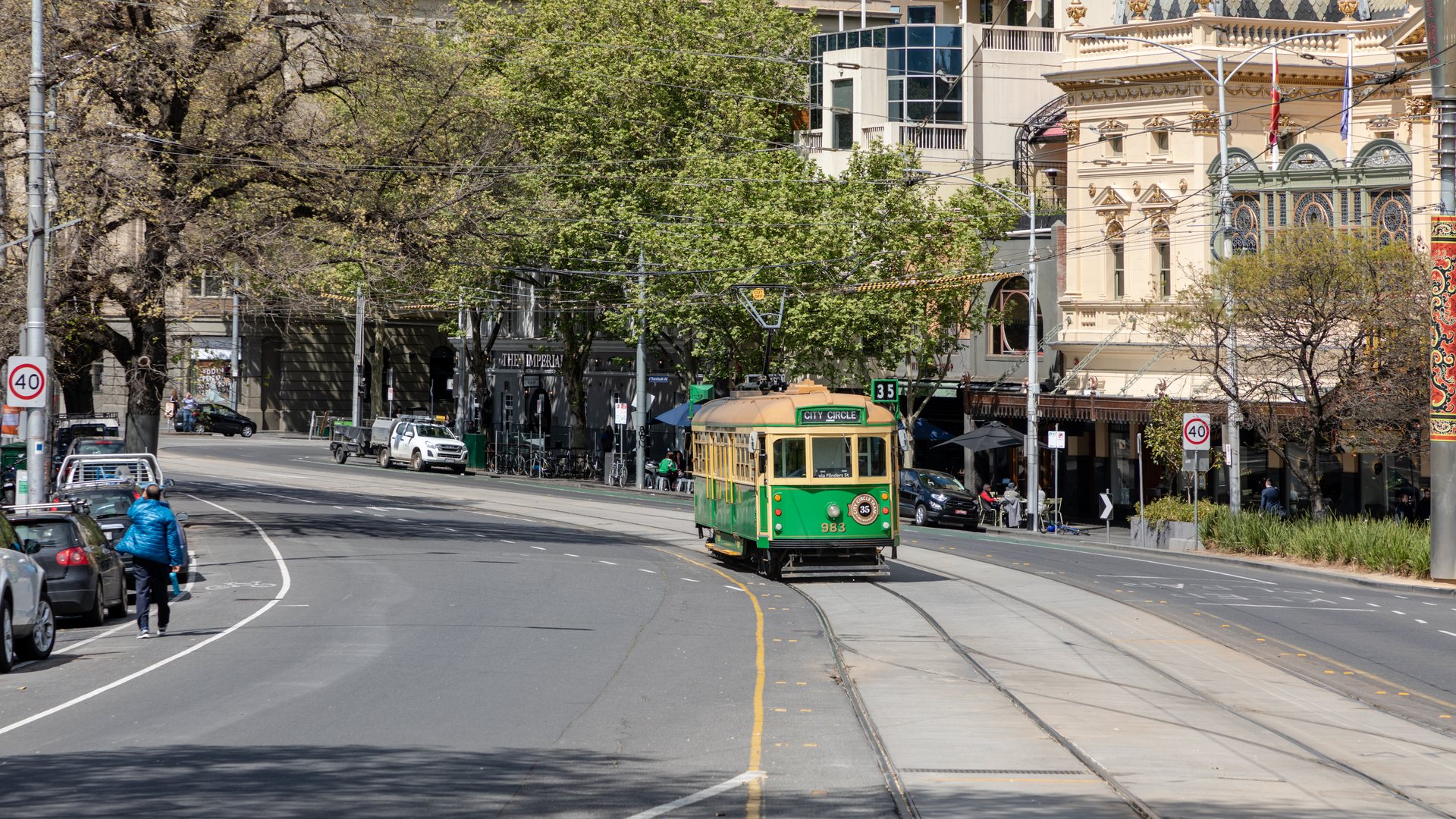 Xe điện City Circle chạy trên đường phố Melbourne giữa các tòa nhà và hàng cây
